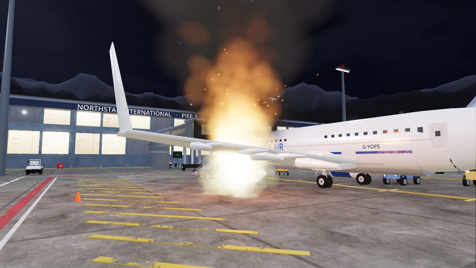 A fire burning under an aircraft wing on a night apron, lighting the concrete.